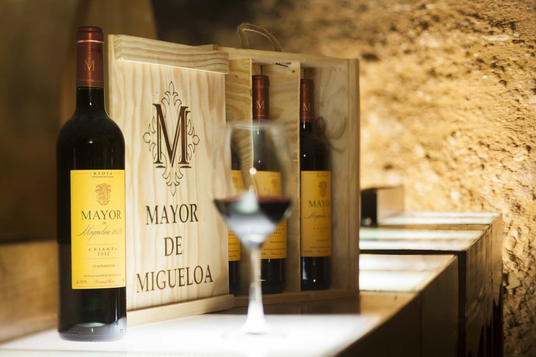 Una botellera de madera con varias botellas de vino y una copa de vino.
