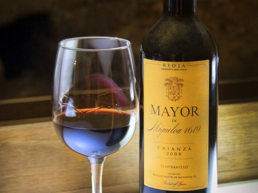 A bottle of Rioja Mayor de Miguel de Miguel 169 wine and a wine glass.