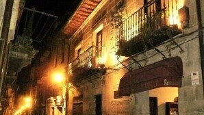 A narrow street at night with a building featuring a restaurant sign.