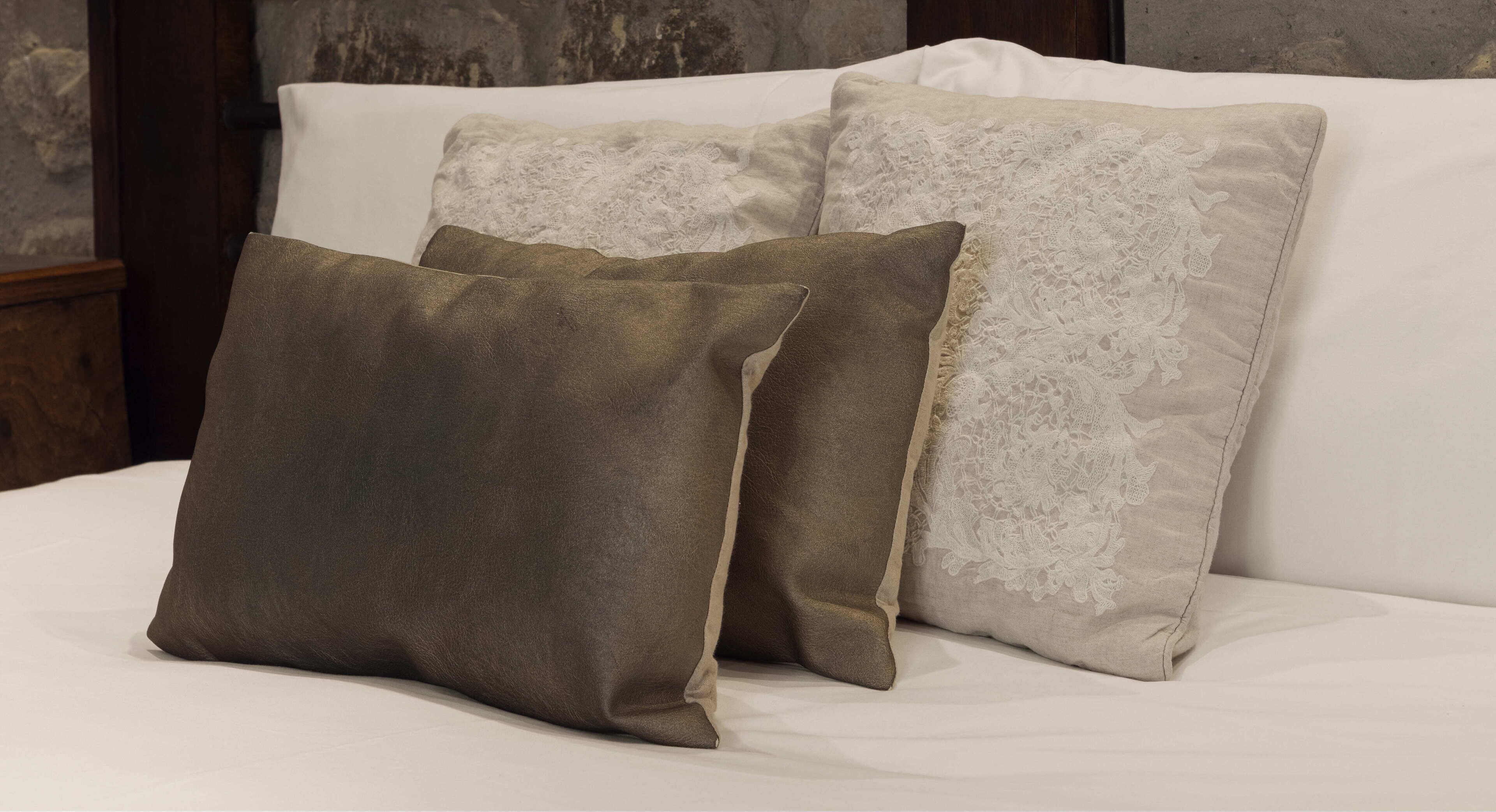A bed with two pillows, one plain and one with lace detailing.