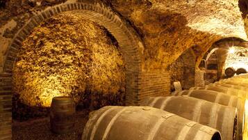Una cantina vinicola sotterranea con volte in pietra e botti di legno.