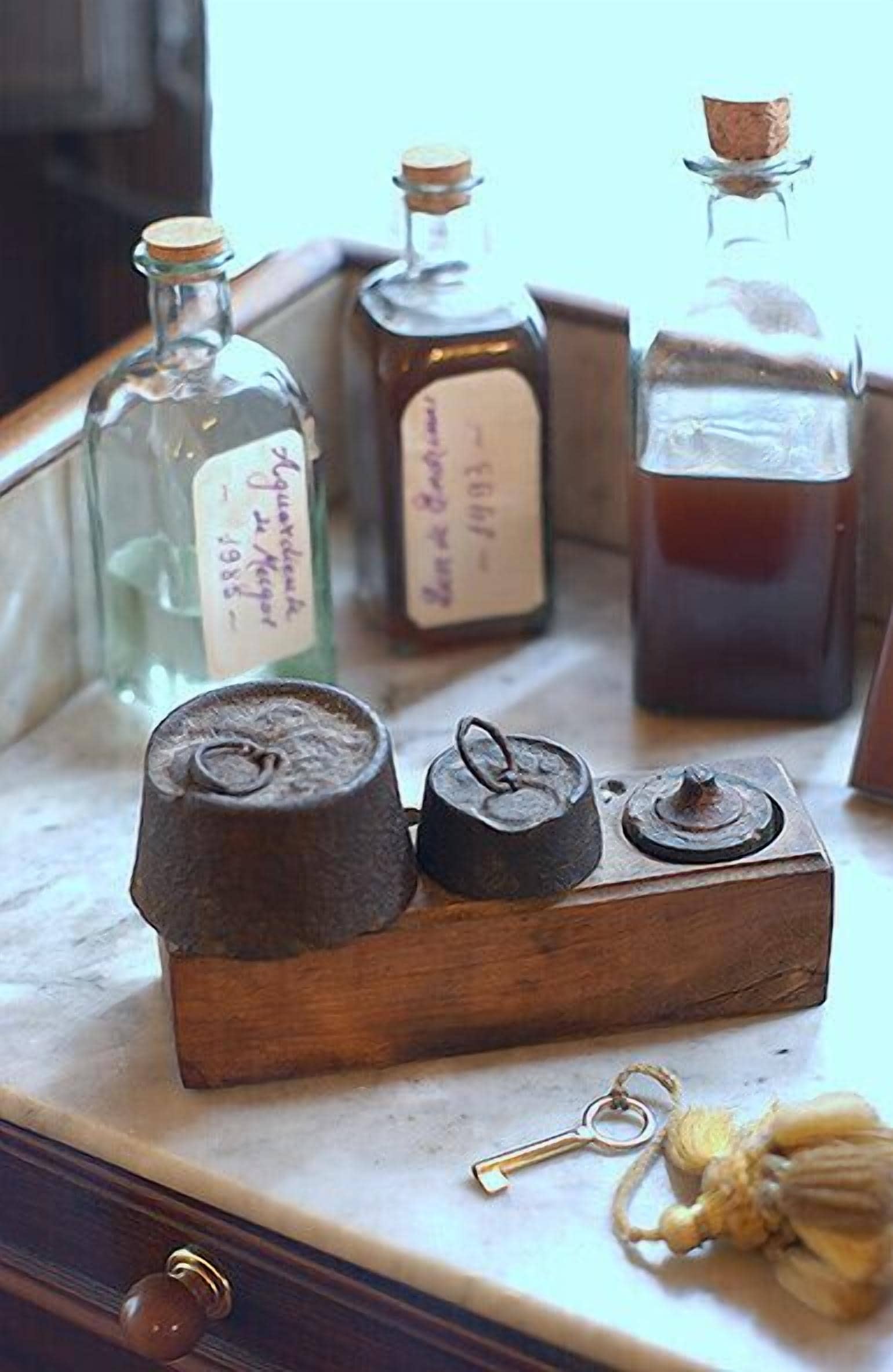 A wooden chest with three metal containers on a marble surface.