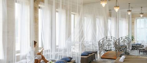 Un cuarto de spa con una cama, una camilla de masaje y una zona de estar con cojines.