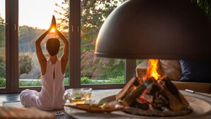 A person meditating by a window with a fire, a cup, and a candle on a table. - Spirit Hotel Thermal Spa (Sarvar)