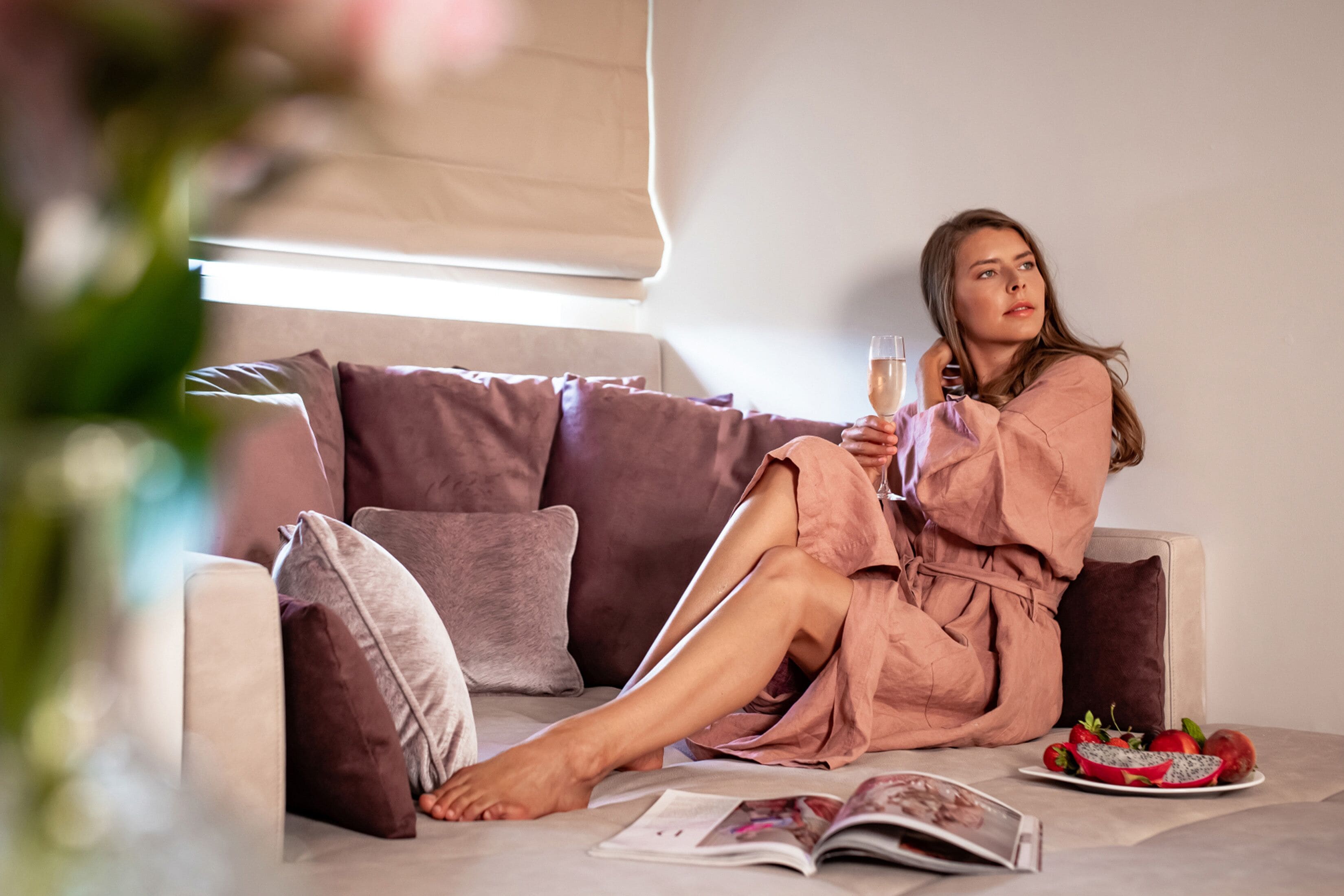 Una persona sentada en un sofá con un plato de fruta y una revista.