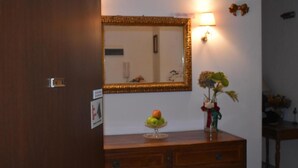 A wooden dresser with a mirror above it, a small vase with flowers, and a fruit bowl on the dresser. - Cittadella (Verona)