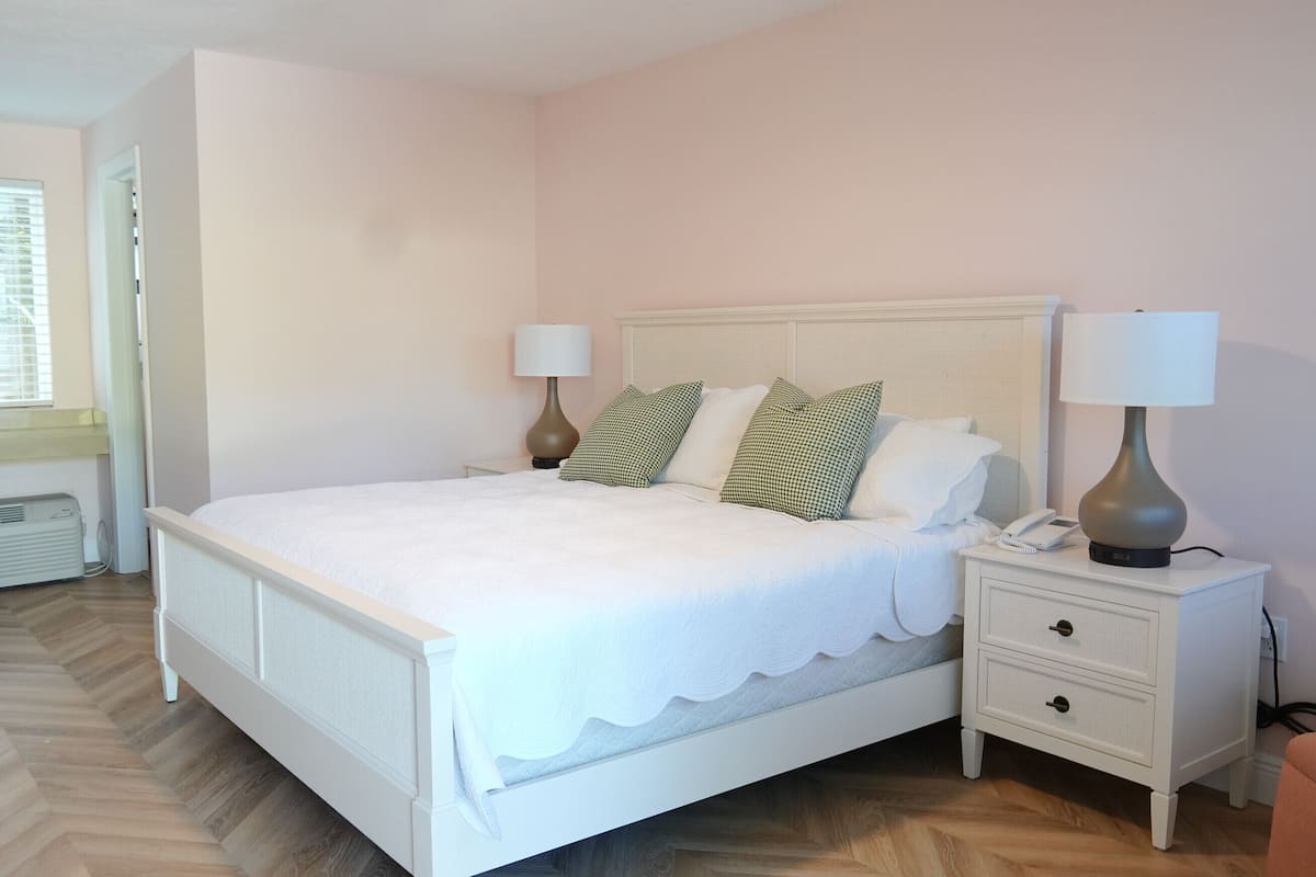 A neatly arranged bedroom with a bed, bedside tables, lamps, and a window.