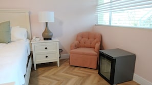 A bedroom with a bed, a nightstand with a lamp, a chair, and a television. - Parkview Motor Lodge (West Palm Beach)