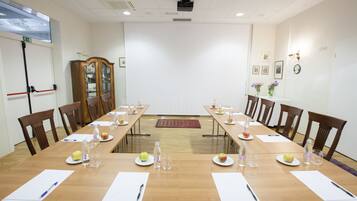 A conference room with a long table, chairs, and various items like plates, apples, and water bottles.