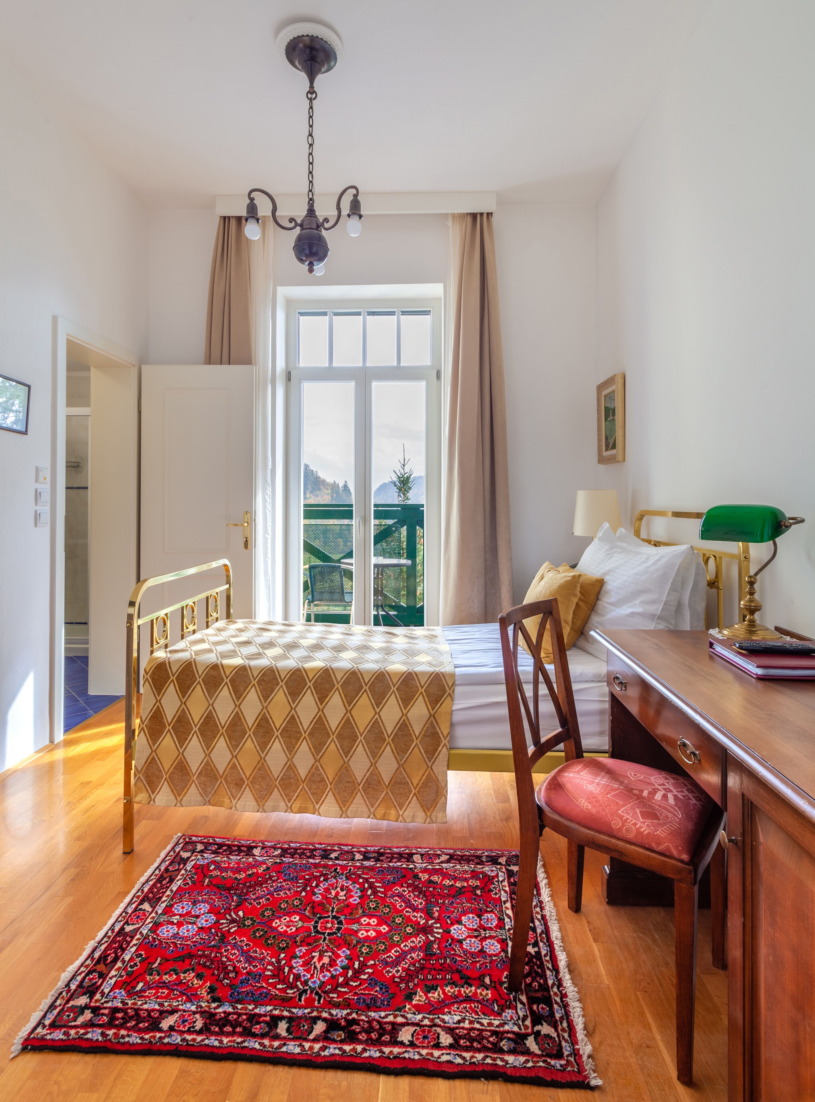 Una camera da letto con un letto, una scrivania, una sedia, un tappeto e vista sull'esterno.