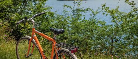 A bicycle parked by a lakeside path with a church in the background.
