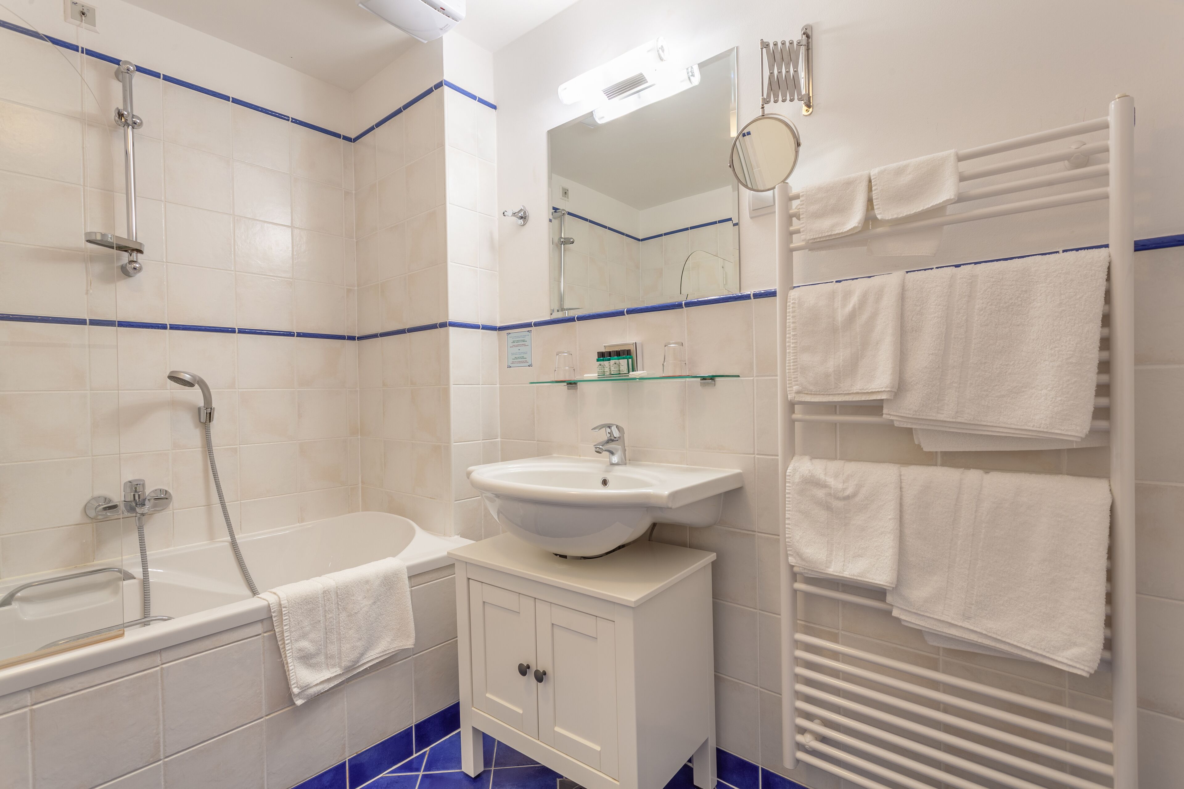 Un baño con bañera, lavamanos, espejo y toallero.