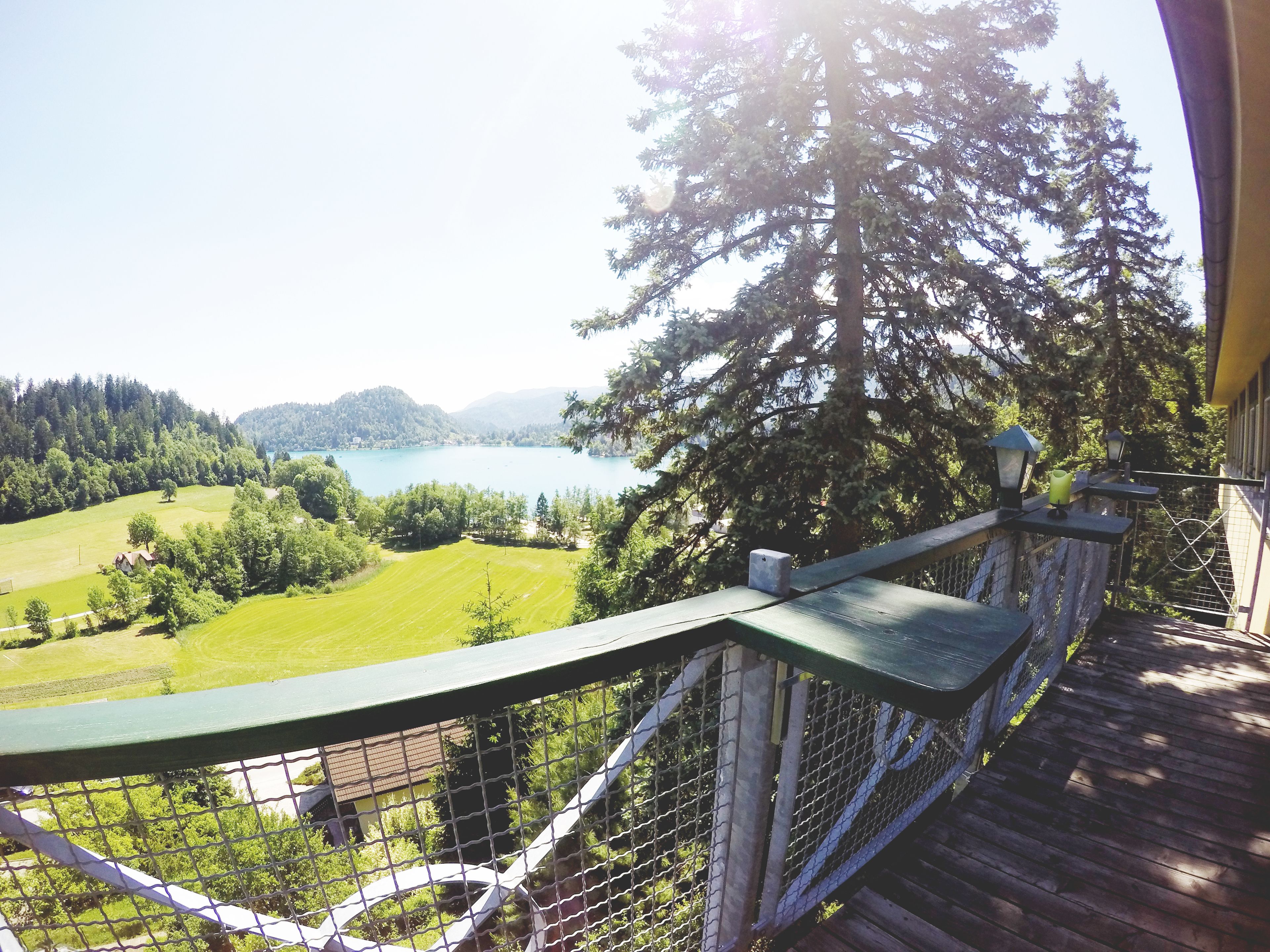 Un balcone con vista su un lago, circondato da alberi e da una zona erbosa.