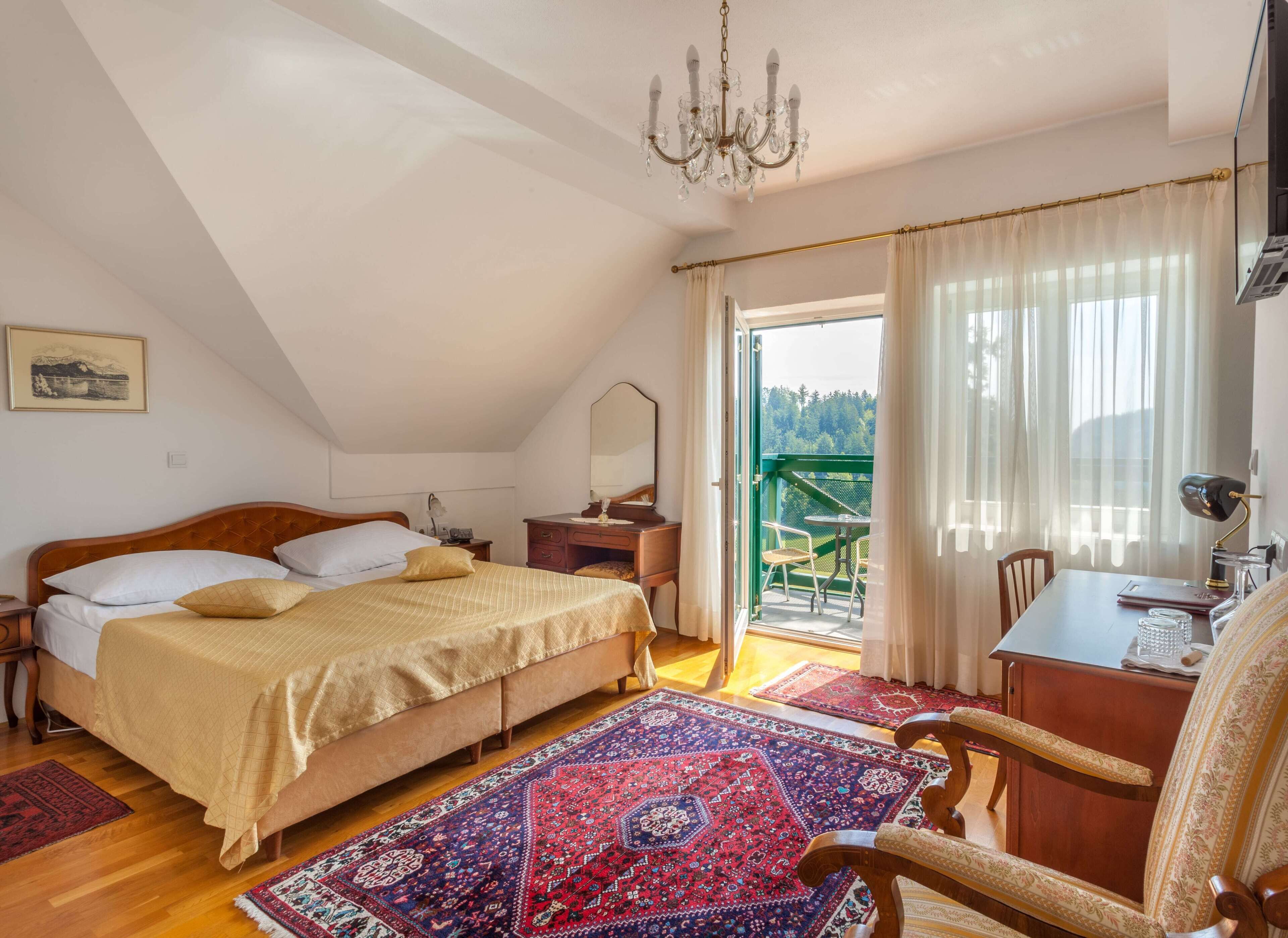 Un dormitorio con cama, mesita de noche, lámpara y vistas a un balcón.
