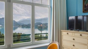 Quarto com uma grande janela que oferece uma vista panorâmica de um lago e montanhas.