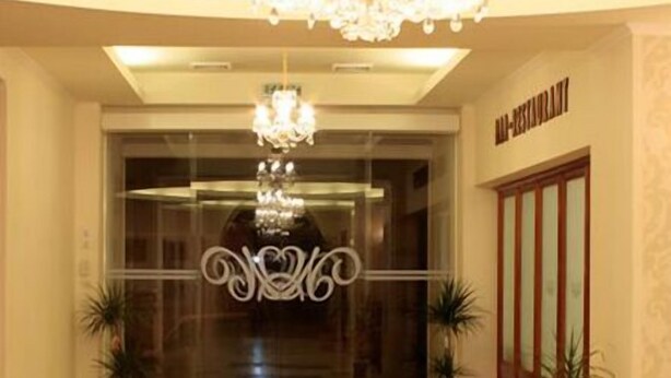 A hotel lobby with a grand chandelier, a reception desk, and potted plants. - Maxim Oradea (Oradea)