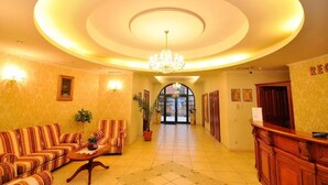 A hotel lobby with a central chandelier, sofas, a reception desk, and a tiled floor. - Maxim Oradea (Oradea)