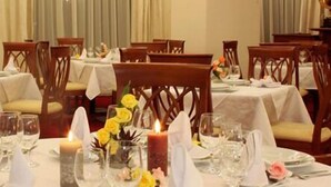 A dining area with tables set for a meal, featuring candles, glasses, and floral centerpieces. - Maxim Oradea (Oradea)