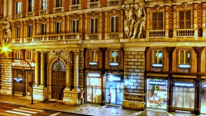 Un edificio histórico con arquitectura ornamentada, que incluye una estatua y una gran entrada arqueada.