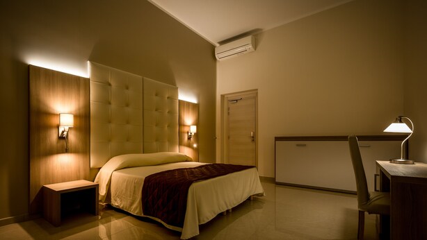 Una habitación de hotel con cama, mesitas de noche, escritorio y una silla.