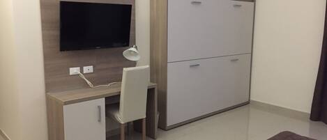 Een kleine slaapkamer met een bed, nachtkastje en een kledingkast.