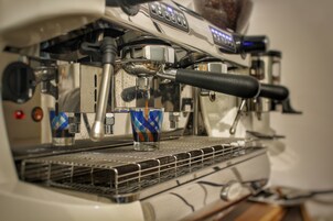 En kaffemaskin med en metalluppsamlingsbricka och en glaskopp.