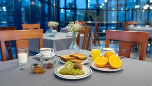 Een ontbijttafel met fruit, toast en sinaasappelsap, in een modern eetgedeelte met grote ramen.