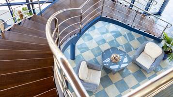 A spacious indoor area with a checkered floor, a staircase, and a seating area with two chairs and a table.