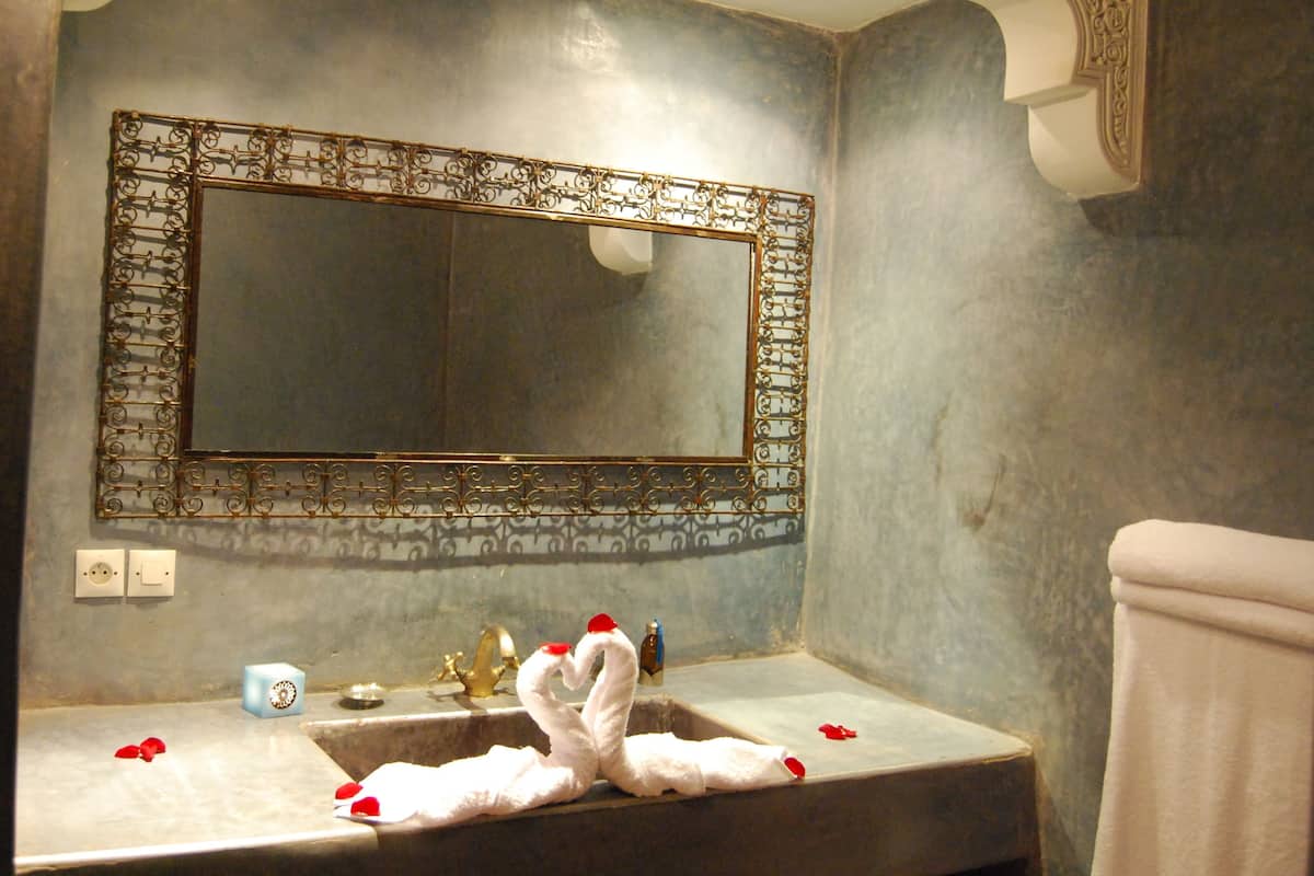 Un baño con un espejo grande, un lavamanos y un perchero para toallas.