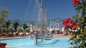 Piscina con fuente de agua, rodeada de sillones de playa y sombrillas.