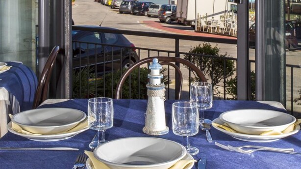 Mesa lista para comer con vista al mar y un faro.