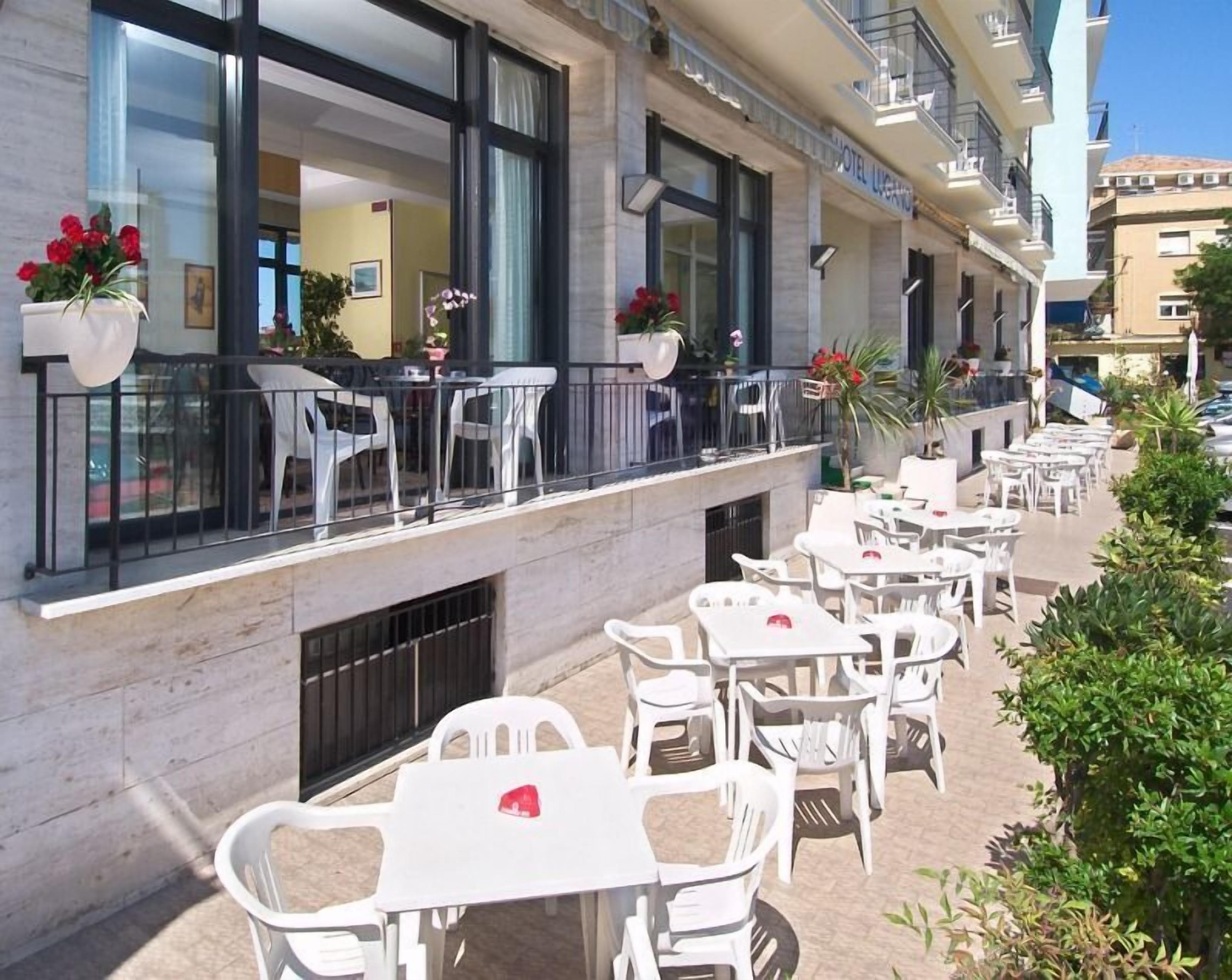 Un hotel con posti a sedere all'aperto, ampie finestre e piante in vaso.