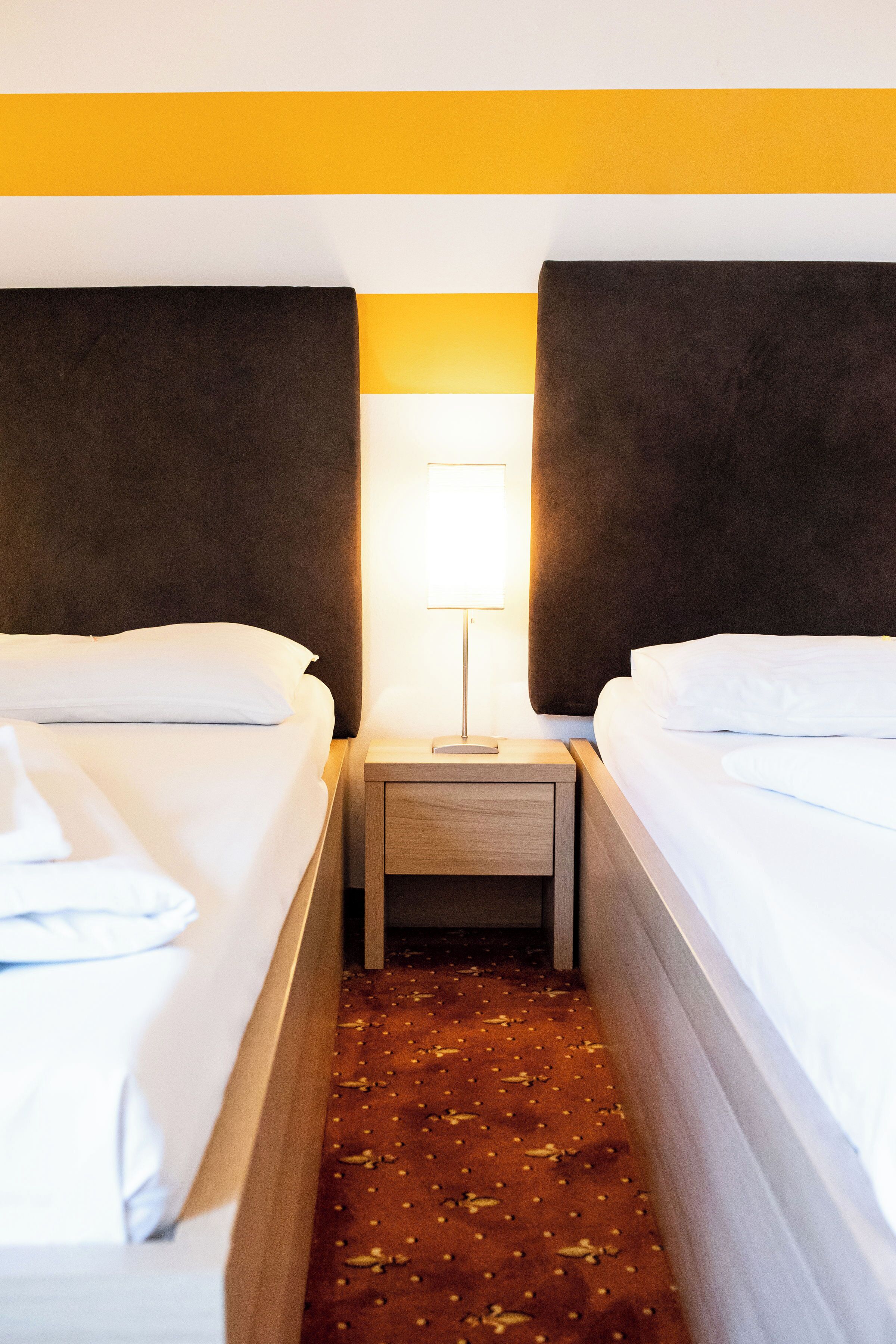 Une chambre d’hôtel avec deux lits, une table de chevet et une lampe.
