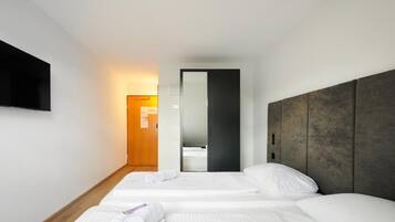 Een hotelkamer met twee bedden, een wandtelevisie en een houten vloer.