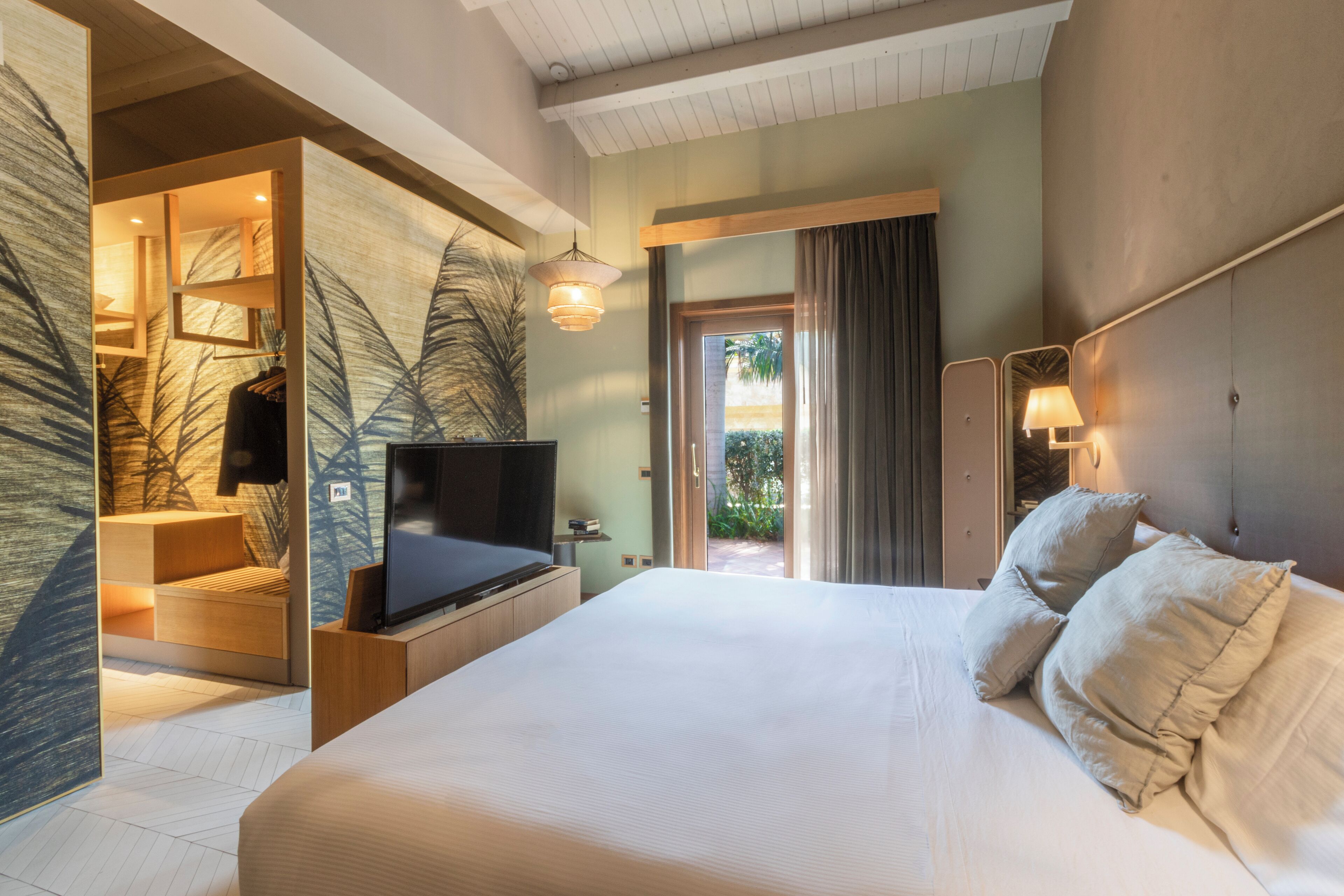 Una habitación de hotel moderna con una cama grande, televisión, escritorio y vistas al exterior.
