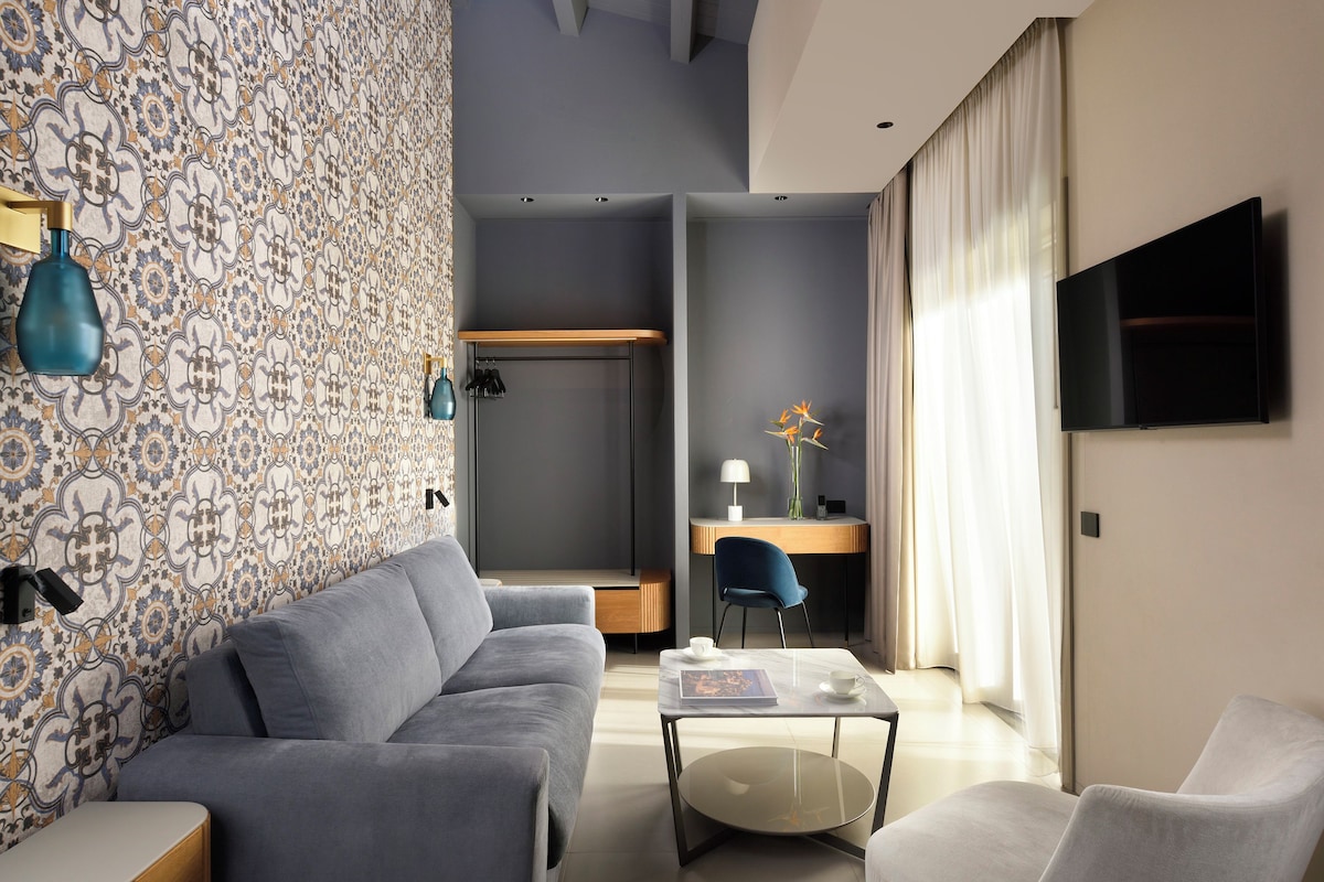 A modern living room with a grey sofa, a coffee table, and a TV mounted on the wall.