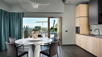 Una cucina moderna con un'ampia isola, pavimento scuro e vista su piscina e giardino.