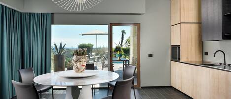 A modern kitchen with a large island, dark flooring, and a view of a pool and garden.