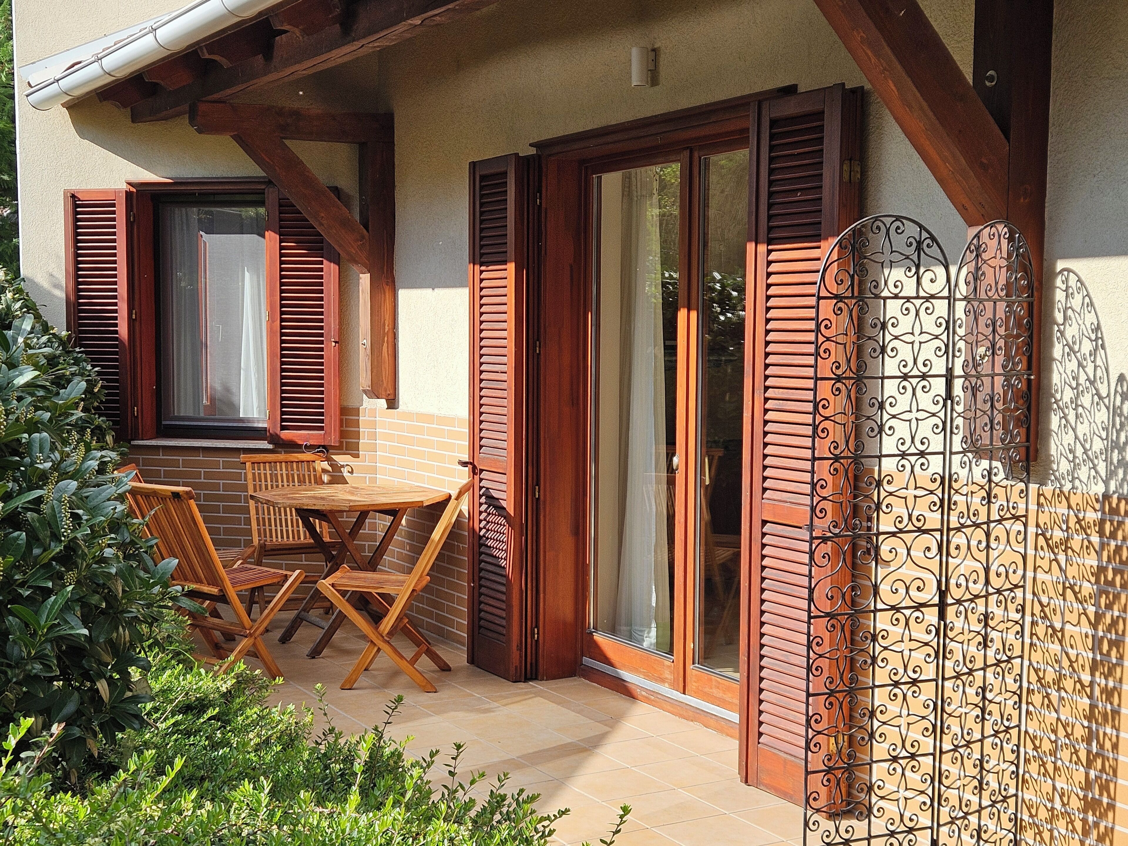 A patio with wooden furniture, a sliding glass door, and a metal gate.