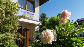 A hotel named "Hotel Kob" with a signboard, surrounded by lush greenery and blooming flowers. - Jakob (Fuessen)