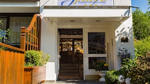 The exterior of Hotel Jakob with a wooden staircase leading to the entrance, a sign above the door, and potted plants around the entrance. - Jakob (Fuessen)