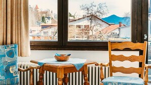 A cozy room with a wooden table, a chair, and a view of a town through a window. - Jakob (Fuessen)