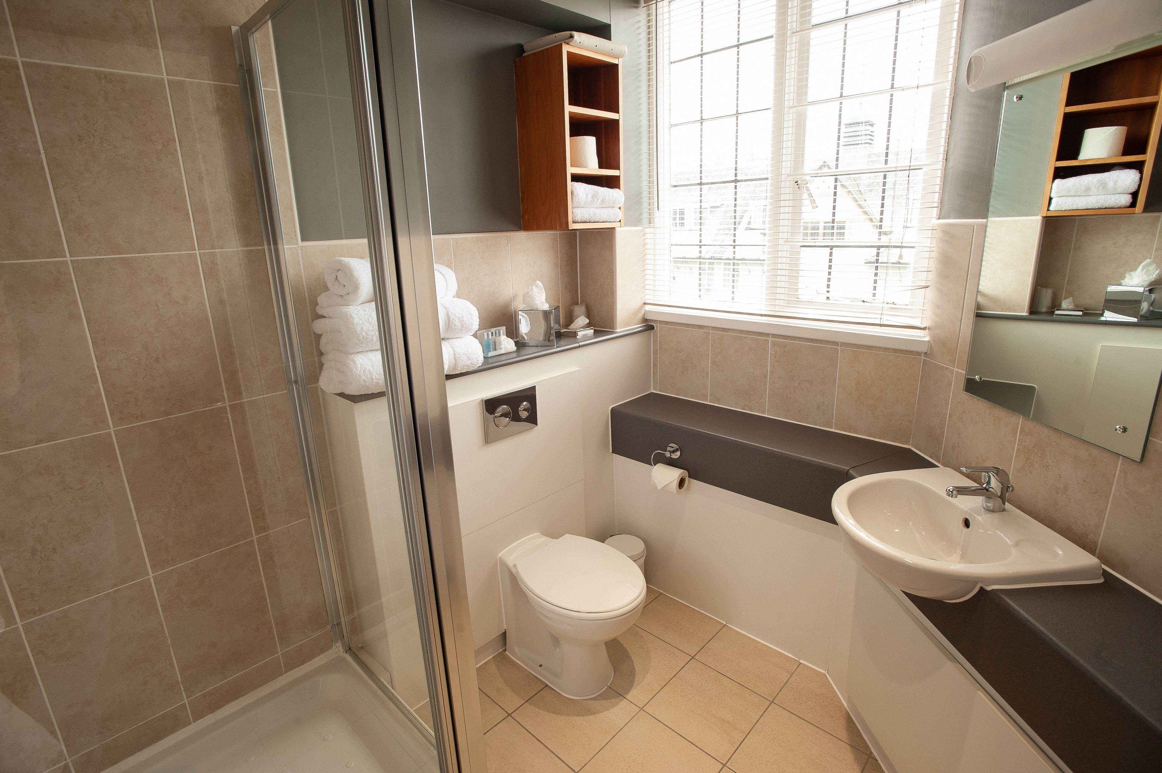 Une salle de bain moderne dotée d’une douche à parois de verre, de toilettes, d’un lavabo et d’un meuble-vasque avec des étagères.