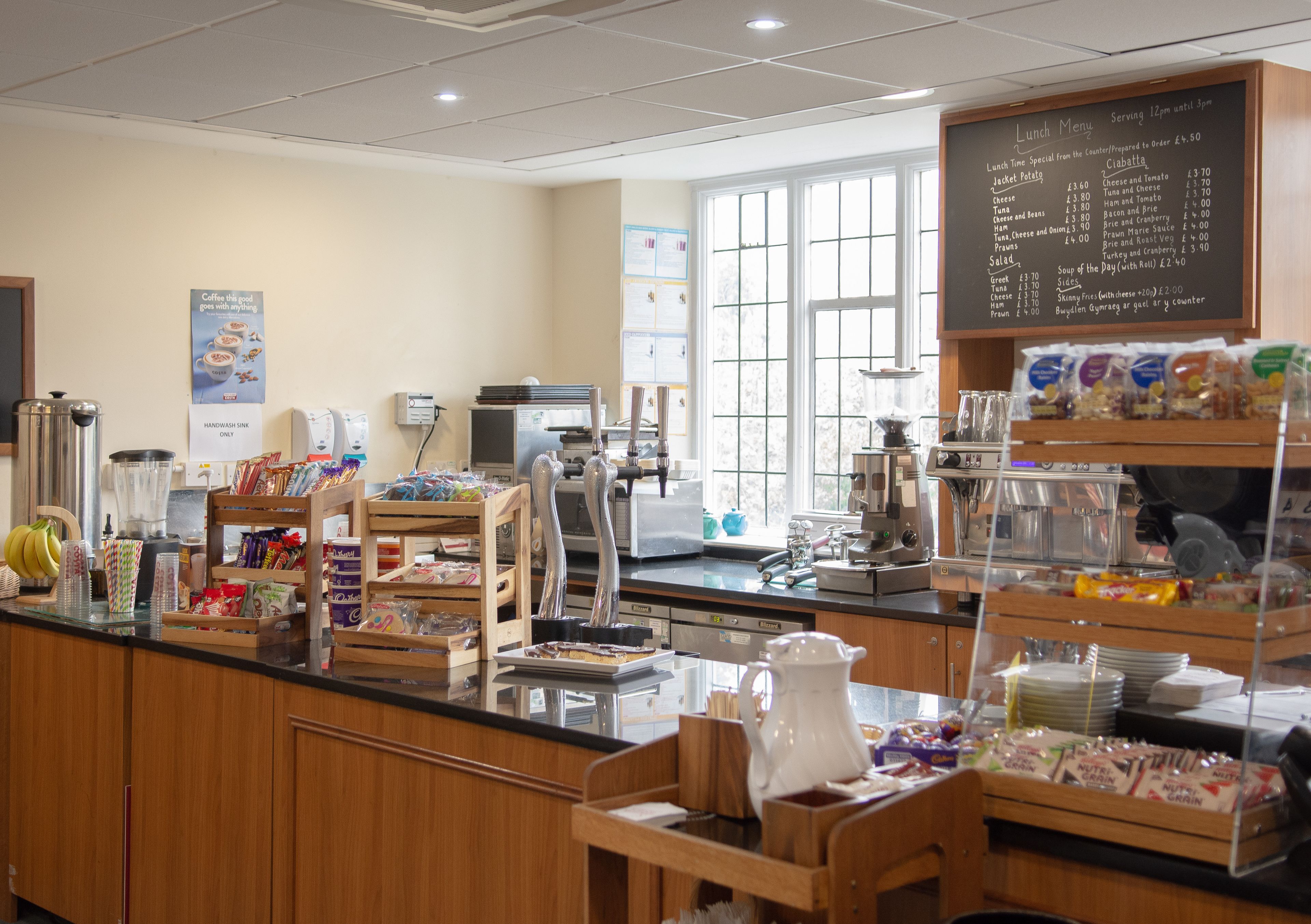 A cafeteria with a menu board, food display, and various kitchen appliances.
