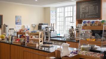 A cafeteria with a menu board, food display, and various kitchen appliances.