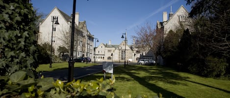 A residential street with stone buildings, a clear sky, and a sign in the foreground.
