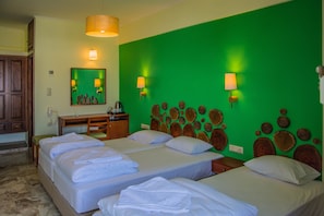 Una habitación de hotel con dos camas, un aparador de madera, un espejo y una pared de acento verde.