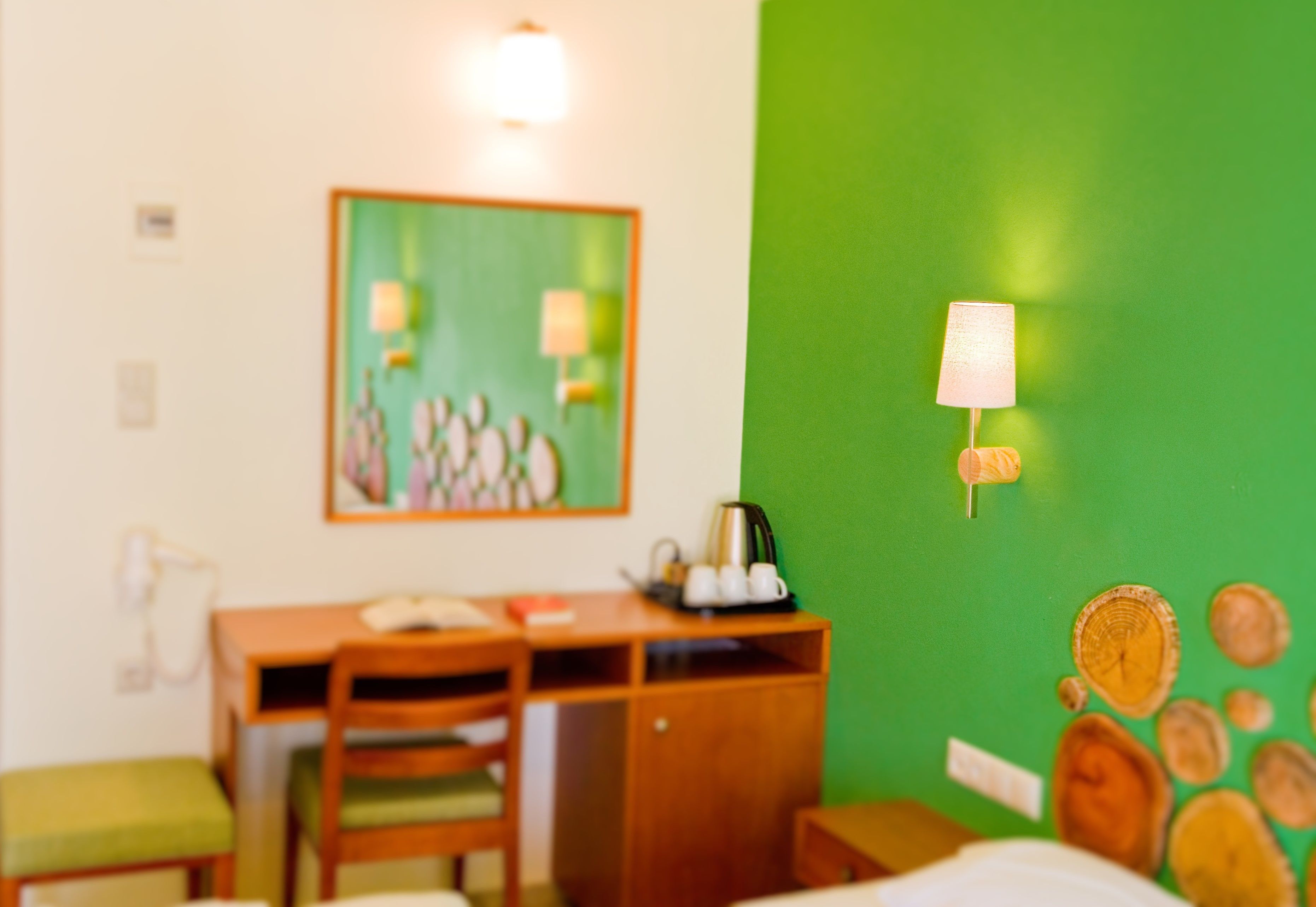 A hotel room with a desk, chair, and a green accent wall.