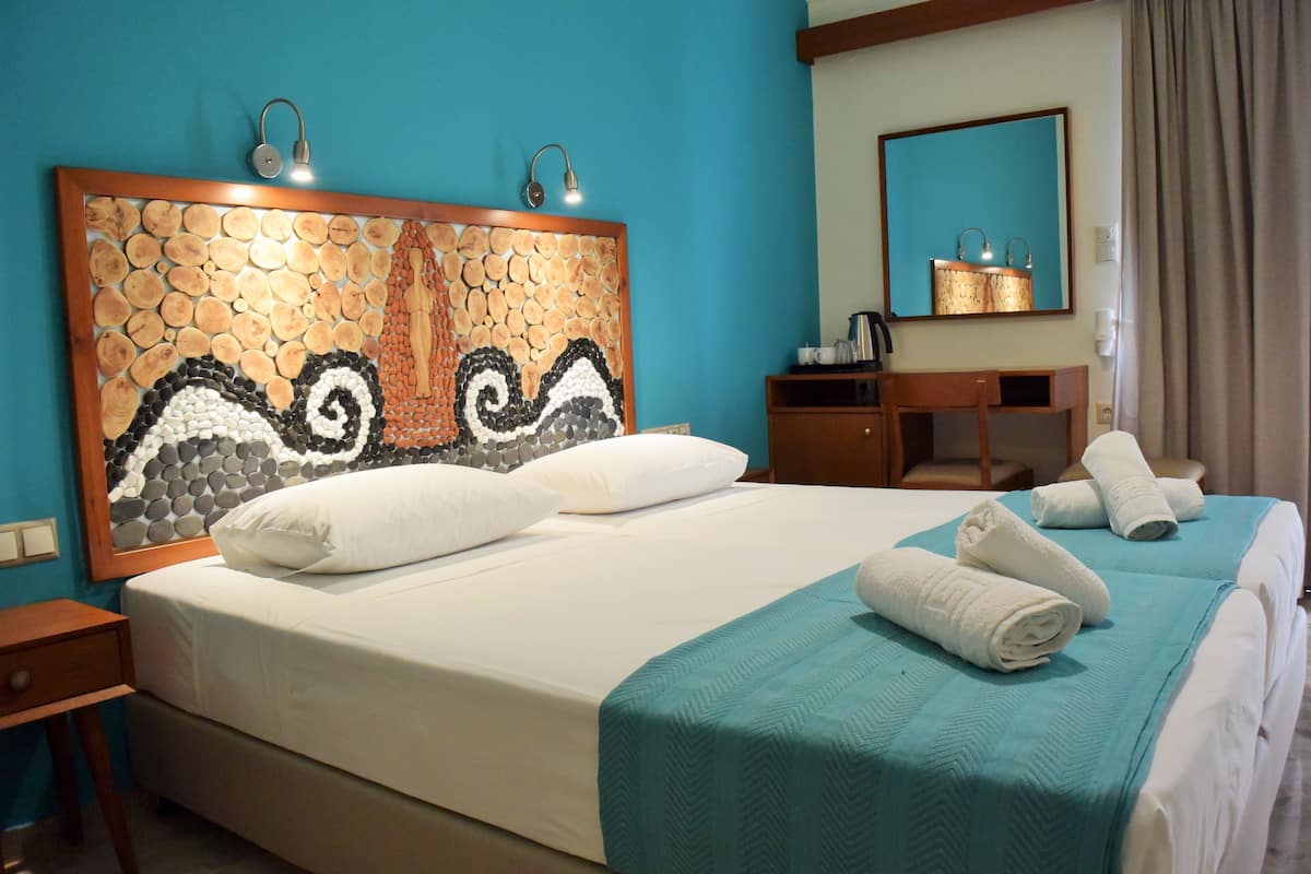 A hotel room with a large bed, a desk, a mirror, and a bathroom.