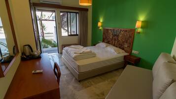 Una habitación de hotel con cama, escritorio, silla, sofá y ventana con cortinas.